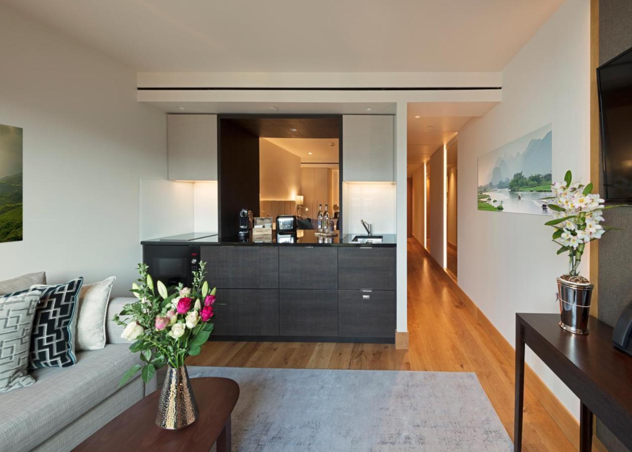 Tower Suites By Blue Orchid London Ngoại thất bức ảnh The photo showcases a modern and stylish interior space, likely a living area of a luxurious apartment or hotel suite. 

- **Bar Area**: There is a sleek bar counter that features a variety of bottles and glassware, suggesting a well-equipped space f
