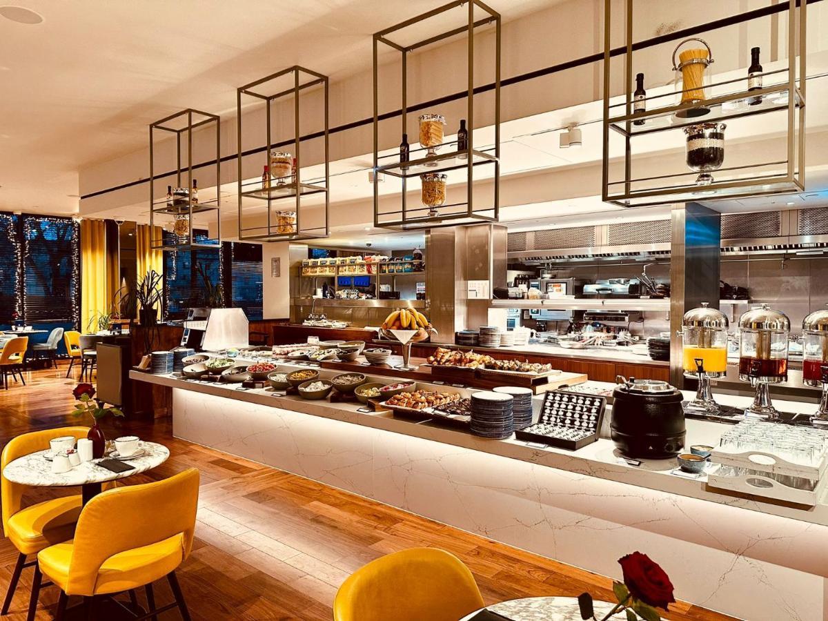 Tower Suites By Blue Orchid London Ngoại thất bức ảnh The photo shows a modern restaurant interior featuring a buffet layout. The space has a sleek design with wooden flooring and a bright, open atmosphere.  

The buffet counter is richly arranged with various dishes and food items, likely for a breakfa