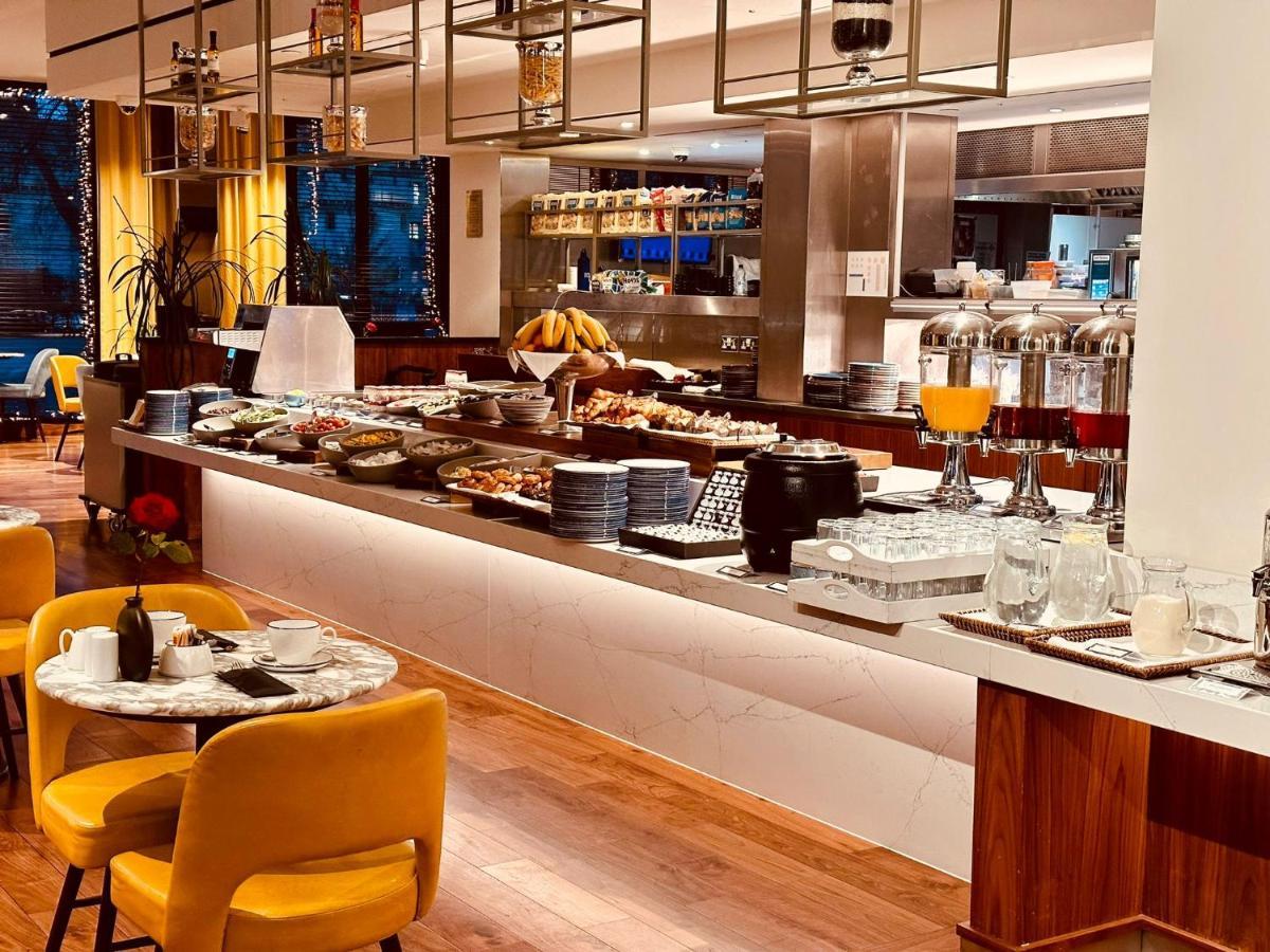 Tower Suites By Blue Orchid London Ngoại thất bức ảnh The photo depicts a modern buffet setting, featuring an array of food items displayed elegantly on a long countertop. There are various dishes, likely including pastries, fruits, and other breakfast items, arranged neatly. In the background, there ar
