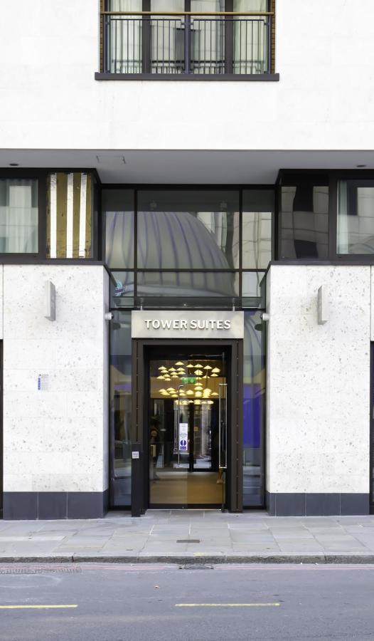 Tower Suites By Blue Orchid London Ngoại thất bức ảnh The photo shows the entrance of a building labeled "TOWER SUITES." The entrance features large glass doors, allowing visibility into the interior. The building has a modern architectural style, with a light-colored stone facade and some decorative el