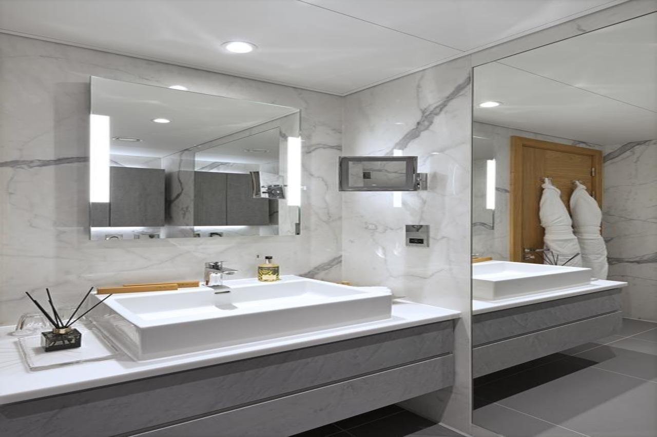 Tower Suites By Blue Orchid London Ngoại thất bức ảnh The photo shows a modern bathroom featuring a sleek design. 

- **Vanity Area**: There is a rectangular sink set into a white countertop, paired with a minimalist faucet. 
- **Mirrors**: Above the sink, there is a large mirror that reflects the entir